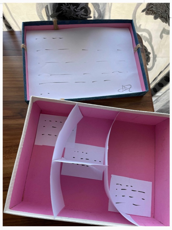 An open box prototype with paper inserts arranged inside it.